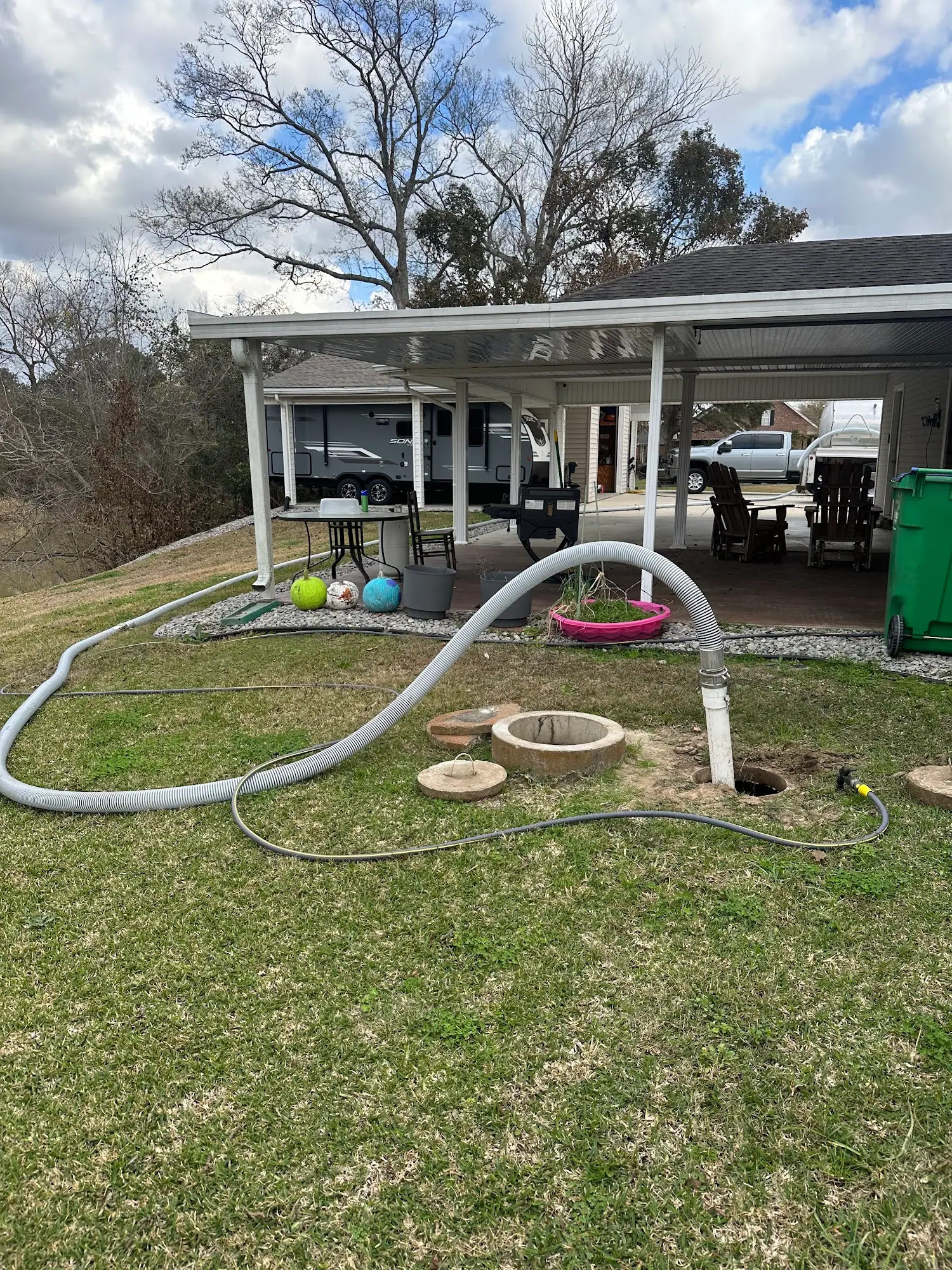 Hoses across a backyard lawn to open tank lids